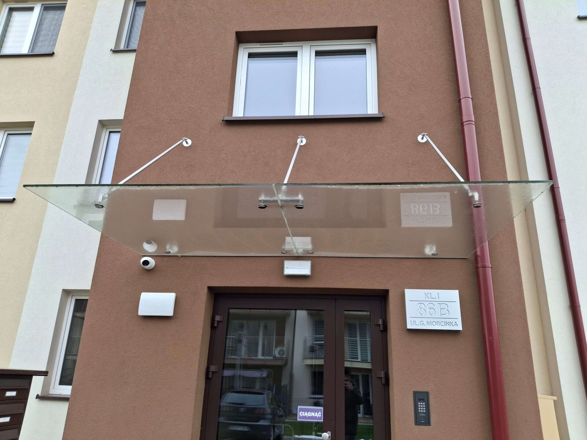 Mycie daszku szklanego nad wejściem do klatki w Krakowie